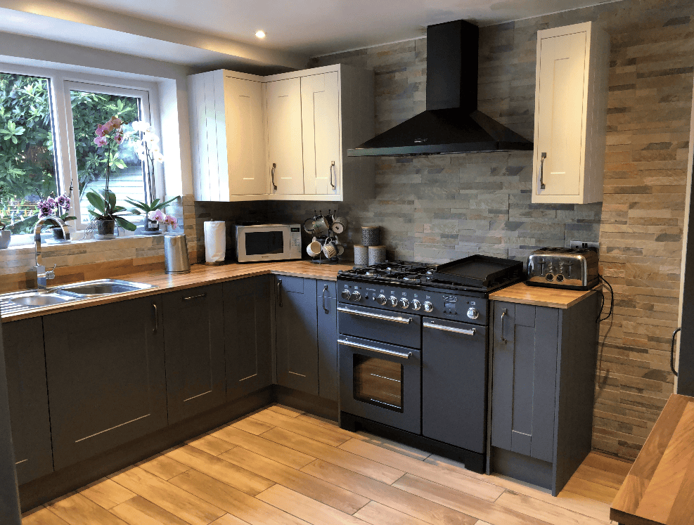 Kitchen with dark and light cabinets, oven, microwave, and window view.