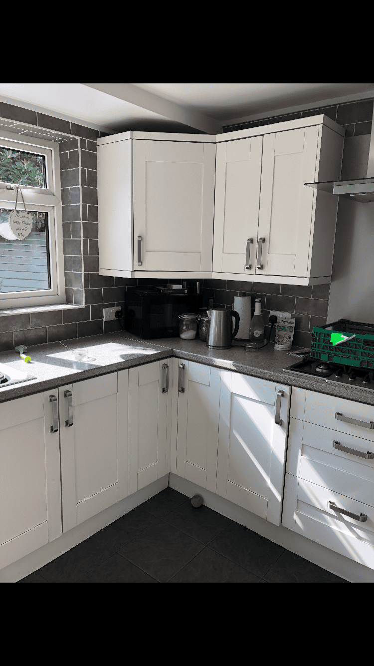 Modern white kitchen cabinets with black countertops and stainless steel handles.