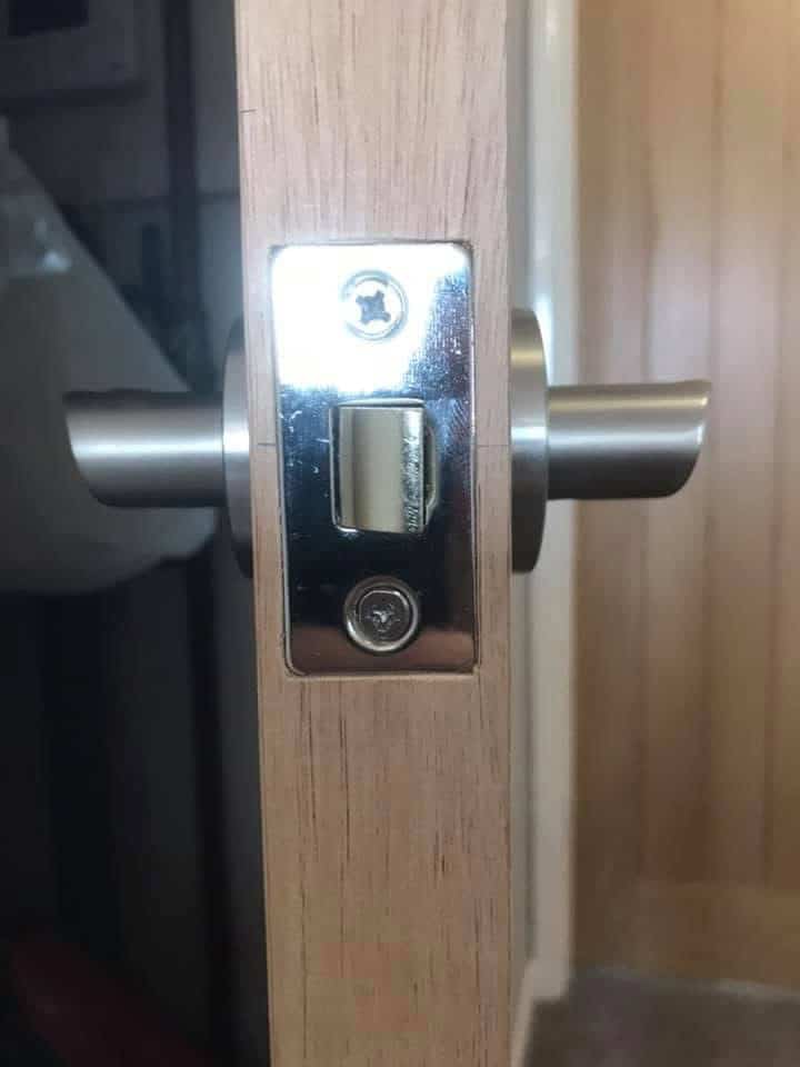Door lock mechanism with handle on wooden door.