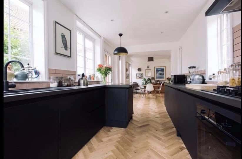 Modern kitchen with black cabinetry, bright natural light, and a spacious open-plan design.