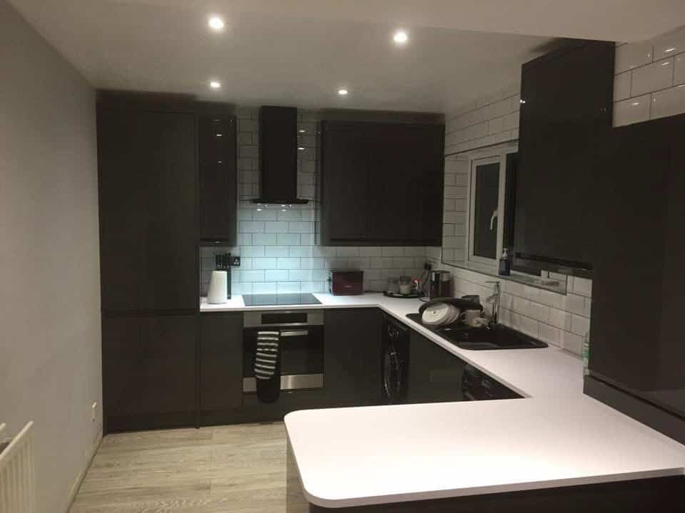 Modern black kitchen with white countertops and subway tile backsplash.