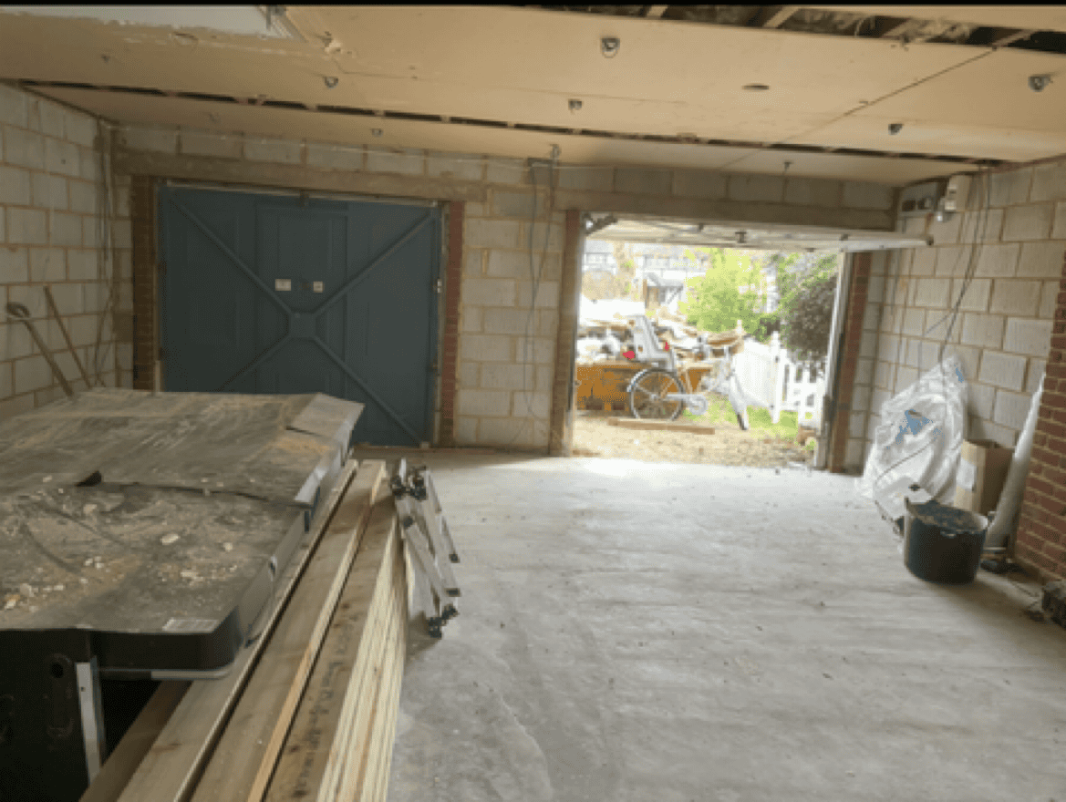 Garage under construction with exposed brick walls and open garage door.