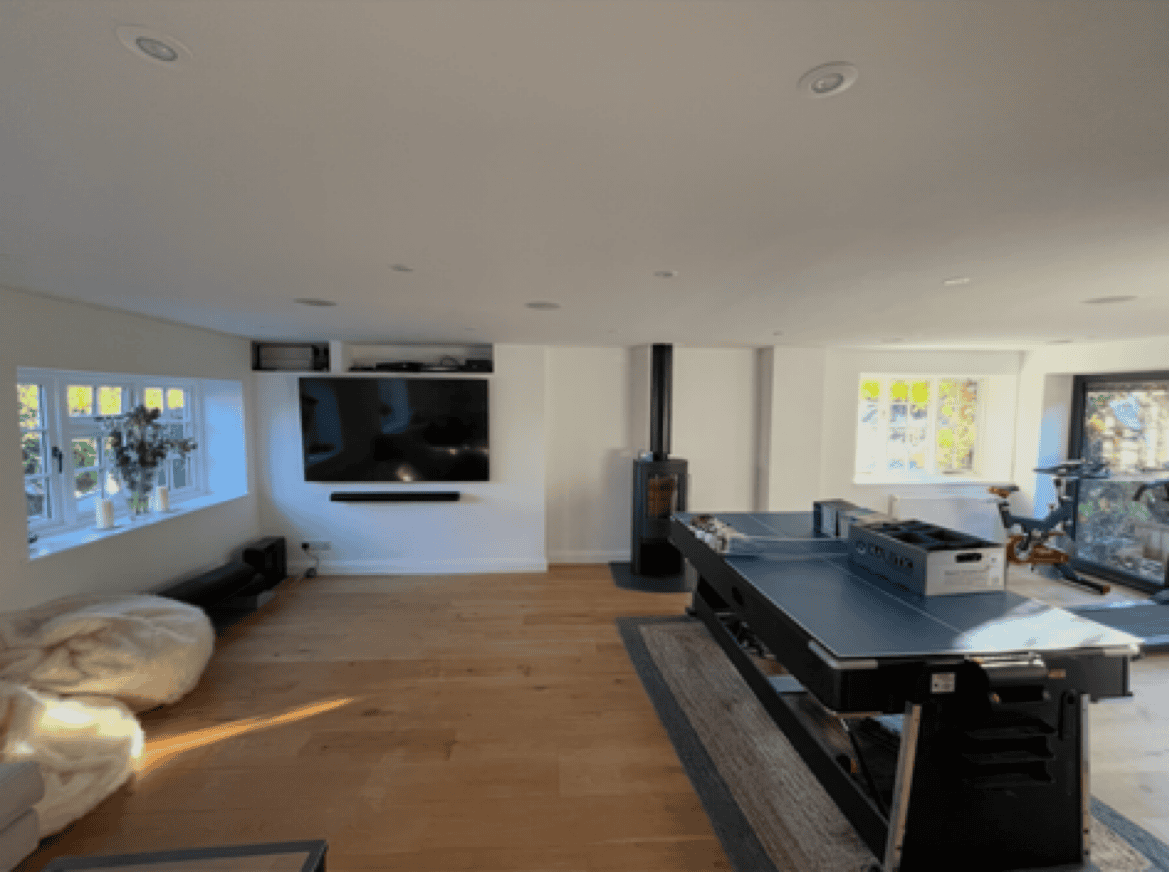 Modern living room featuring a fireplace, wall-mounted TV, and large windows for natural light.