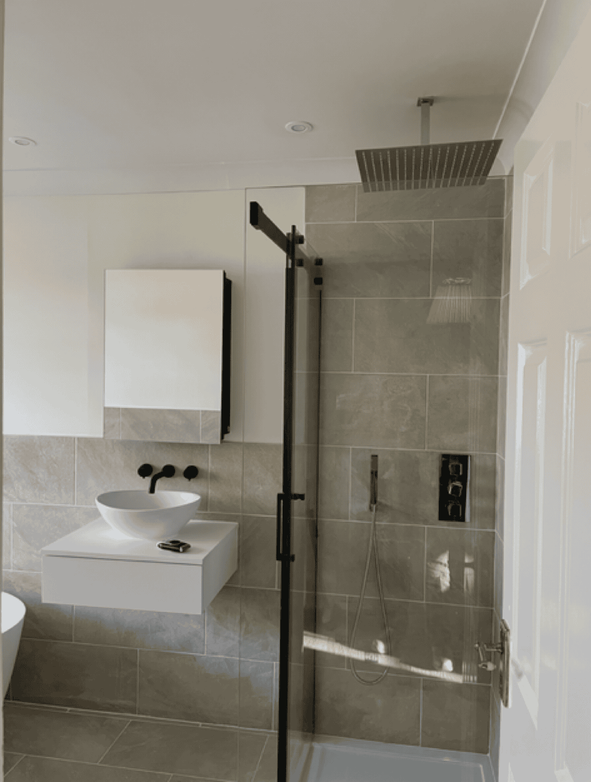 Modern bathroom with walk-in shower, rainfall head, and contemporary fixtures.
