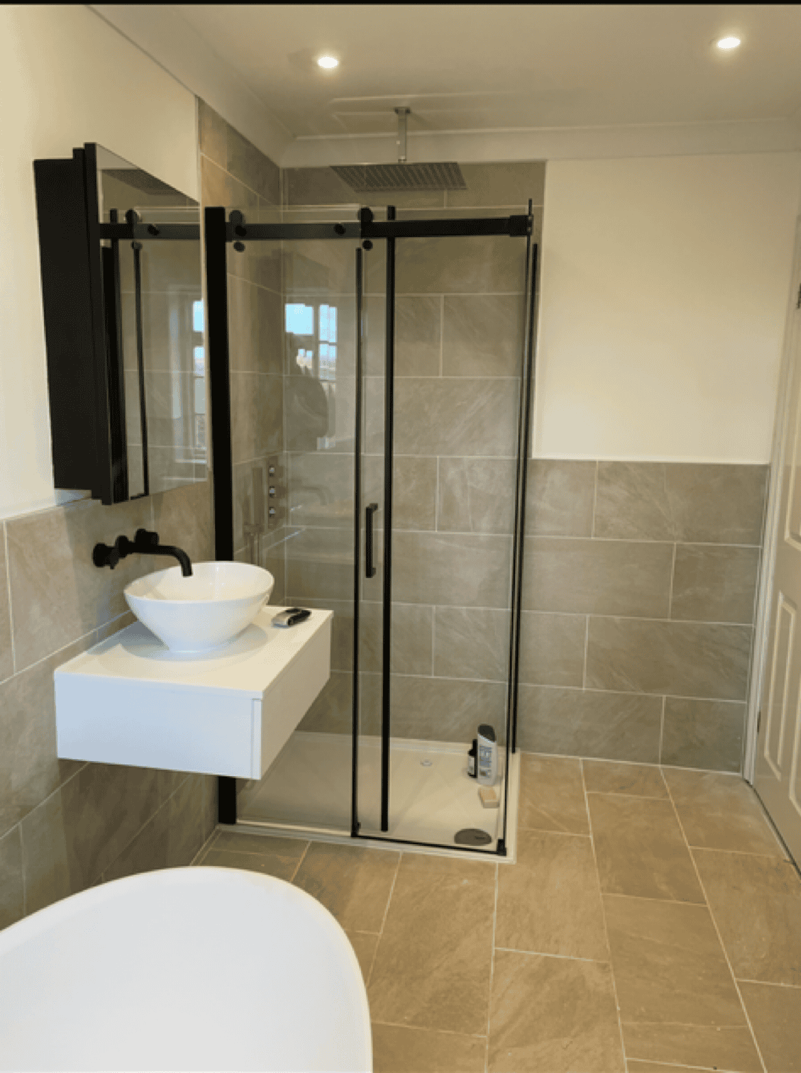 Bathroom with walk-in shower, modern sink, and stylish tiling.