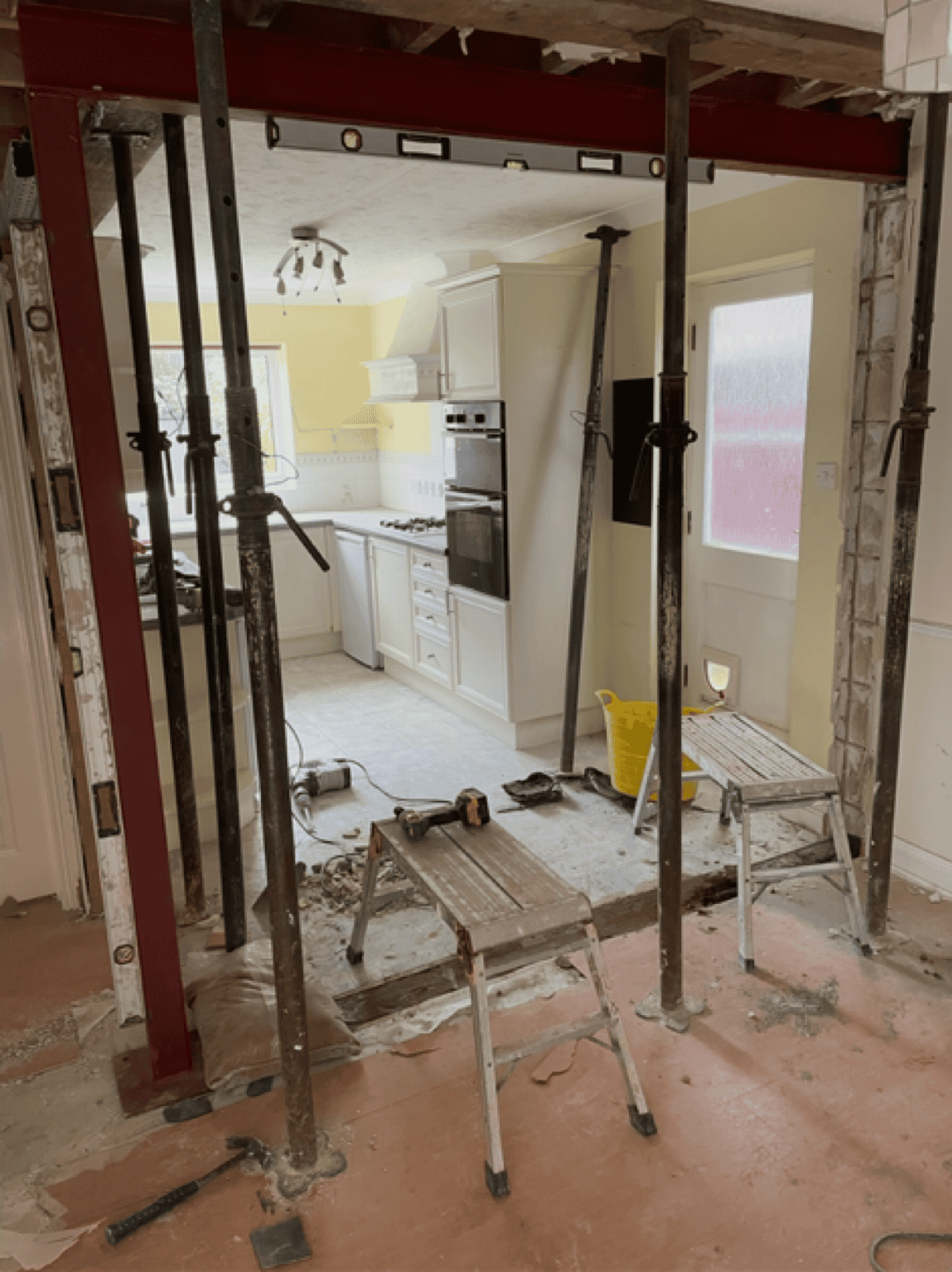 Kitchen renovation with new cabinetry and structural support in progress.