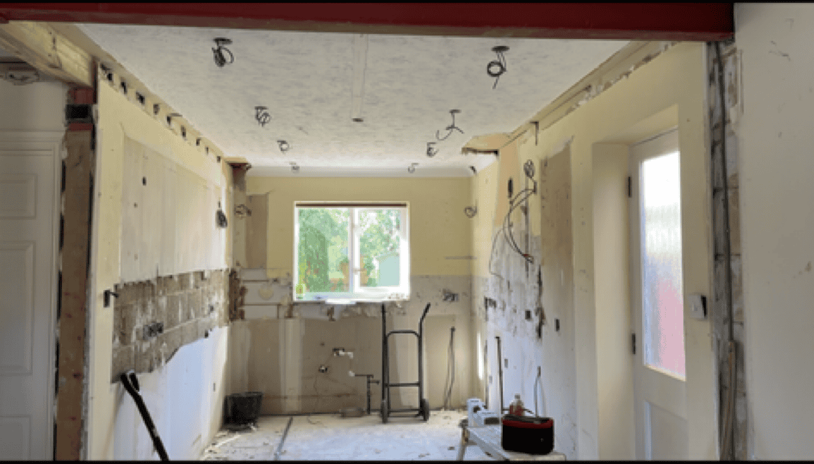 Renovation of a kitchen space with exposed walls and construction tools.