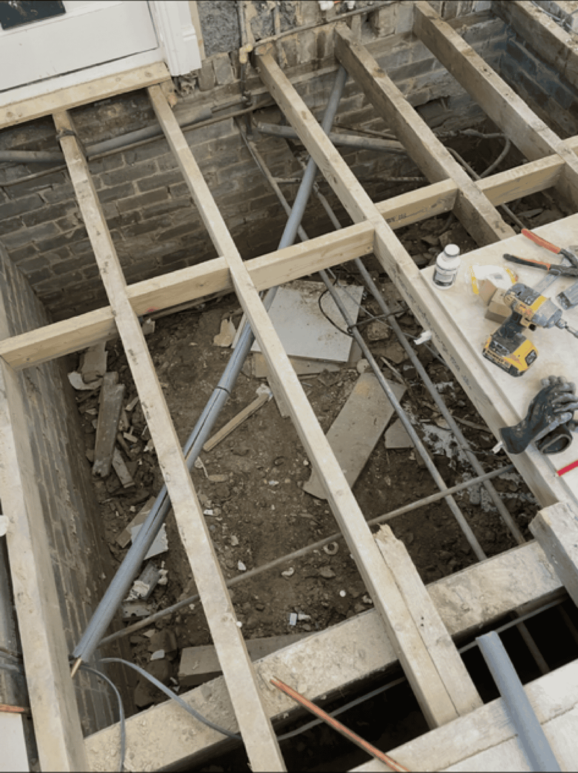 Wooden building framework with tools and materials on site.