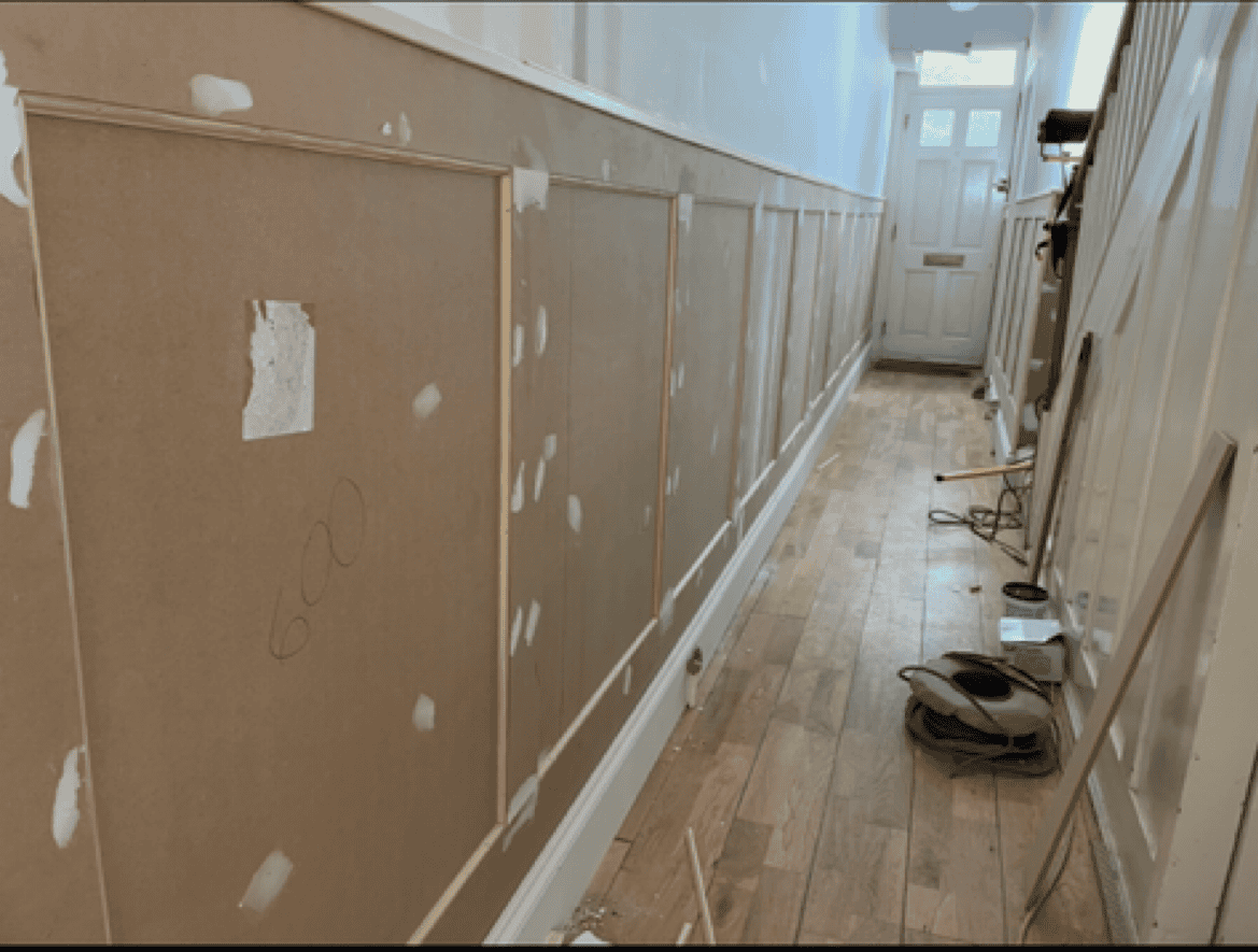 Interior wall paneling installation in a hallway under renovation.